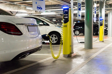 Electric car (new energy vehicle, NEV) is charged from the charging station in the parking lot of...