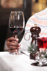 African American hand holding a glass of red wine. Hand in focus. Macro photo, photo in the interior.