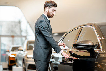 Elegant businessman choosing new luxury car in the showroom