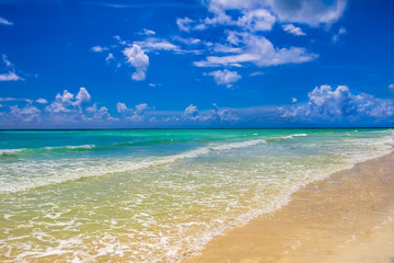 Turquoise water on a tropical sandy beach with beautiful clouds in the sky in the Caribbean sea, Freeport, Bahamas