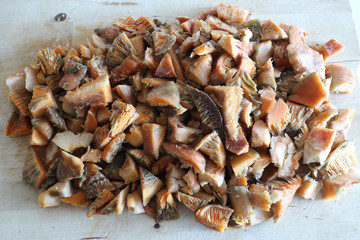 Minced saffron milk cap mushrooms (Lactarius deliciosus) caps, similar to Lactarius Sanguifluus and Lactarius Deterrimus, on a wooden cutting board