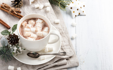 Cup of hot chocolate with marshmallow cinnamon sticks on the white wooden table. Winter cocoa drink...