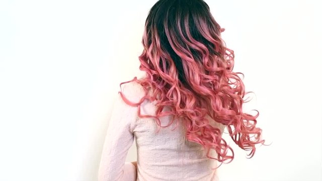 Beautiful long ombre dyed curly hair. Sexy brunette model girl with  wavy black and pink gradient color hair. Hairstyle, extensions. Slow motion 4K UHD video footage. 3840X2160 