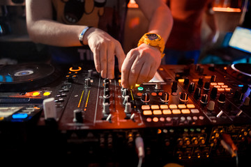 Dj mixes the track in the nightclub at party. In the background laser light show