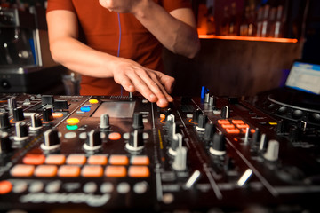 Dj mixes the track in the nightclub at party. In the background laser light show