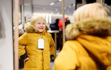 Cute little boy trying new coat during shopping