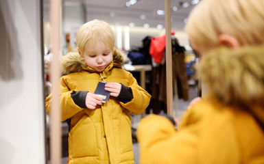 Cute little boy trying new coat during shopping
