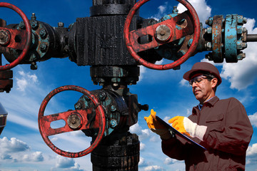Engineer with clipboard inspecting oil field equipment low angle shot 