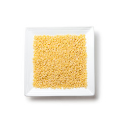 Uncooked pasta stars on white square plate on white background isolated