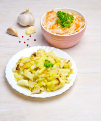 salted cabbage in a plate next to pepper peas and garlic, parsley fried potatoes in a plate 