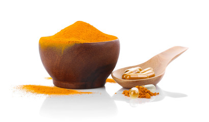 Turmeric , turmeric powder in wooden cup with wooden spoon and turmeric capsules on white.