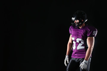 American football player wearing uniform on dark background. Space for text