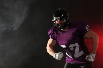 American football player wearing uniform on dark background. Space for text