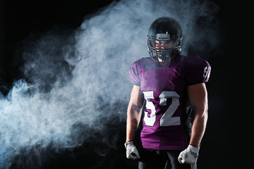 Fototapeta na wymiar American football player wearing uniform on dark background. Space for text