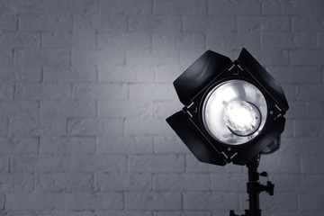 Professional photo studio lighting equipment near brick wall. Space for text
