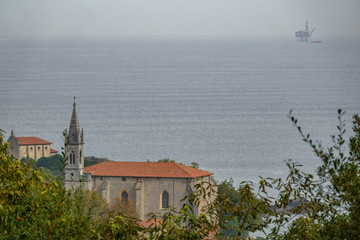 Mundaka church with gas ocean platform in the horizon