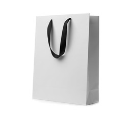 Paper shopping bag with ribbon handles on white background. Mockup for design