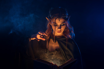 Red haired elf in silver tiara learning spells from book.