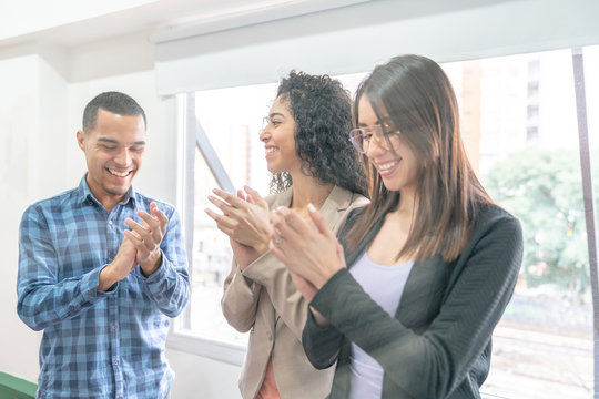 Two girls at the office making applause to a colleague for his success in business