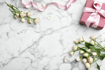 Flat lay composition with beautiful roses and gift box on marble background. Space for text