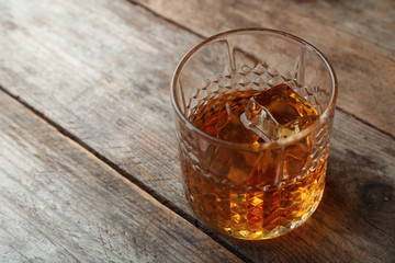 Golden whiskey in glass with ice cubes on table. Space for text