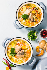 Fish soup with salmon, vegetables and couscous in blue pots. Top view, space for text.