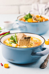 Fish soup with salmon, vegetables and couscous in blue pots. Selective focus, space for text.