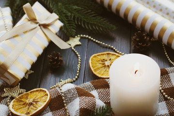 Christmas background with gift boxes, oranges, burning candle on the table. Golden decor for xmas.
