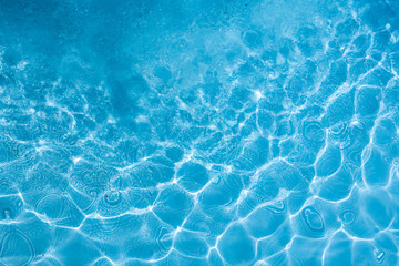 Background of rippled pattern of clean water in a blue swimming pool.