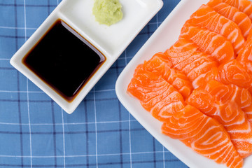 Salmon raw sashimi on whiteJapanese traditional dish on blue tablecloth.