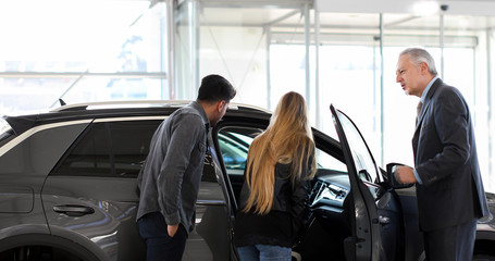 Fototapeta na wymiar Car dealer showing a car to a couple