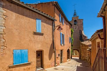 Fototapeta na wymiar Belltower in Roussillon. Tower and houses with red ocher color, Roussillon, Provence, Luberon, Vaucluse, France