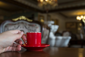 Close up of women's hands holding a red cup of coffee in the cafe concept.