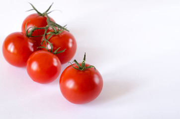 Red juicy cherry tomatoes with green tails lying on a white background