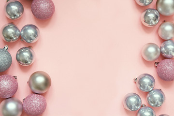 Christmas pink and silver baubles as frame on pastel pink background. Top view with space for text.