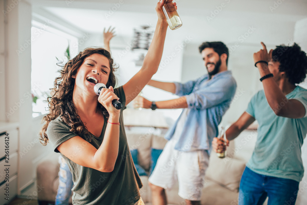 Wall mural group of friends playing karaoke at home. concept about friendship, home entertainment and people