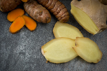 turmeric slices and ginger root sliced on gray background