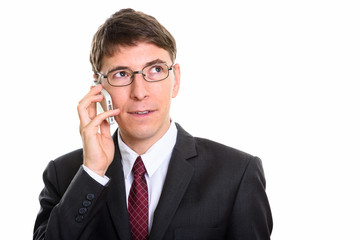 Studio shot of businessman talking on mobile phone while thinkin