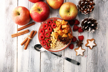 Bowl of oatmeal porridge with banana, apples,raspberries coconut and caramel sauce on rustic table, hot and healthy food for Breakfast