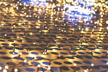 Obraz premium Christmas lights of garland on a metal grill with circles, cream color