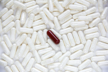Fototapeta na wymiar one brown dissimilar capsule lie on a white capsules