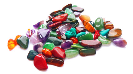 Spilling assorted natural bright coloured semi precious gemstones and gems on white background