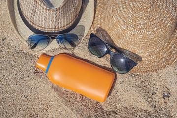 Sun hats, sunglasses and sunscreen protection cream are laying on the sand near, illustarting happy family   holiday.