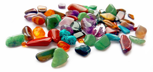 Spilling assorted natural bright coloured semi precious gemstones and gems on white background