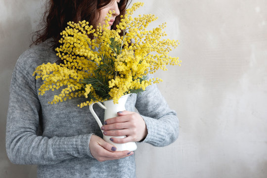 girl with a bouquet of mimosa near an empty wall
