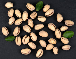 Handful of pistachios on a black background - healthy snack. Top view.