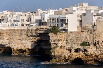 Traditional houses on dramatic cliffs with caves rising from Adriatic sea in Polignano a Mare, Italy, sunny summer day