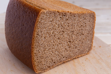 half brick Brown brewed bread from rye flour, on wooden desk background, closeup, traditional russian