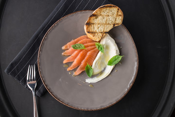 Slices of salmon, cream cheese and grilled bread toast top view on black background