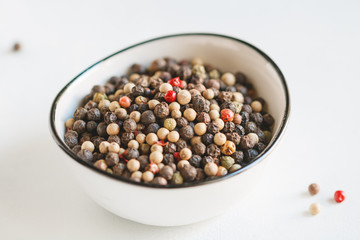 Various kinds of pepper seeds in a white bowl on a white background. Macro photography.
